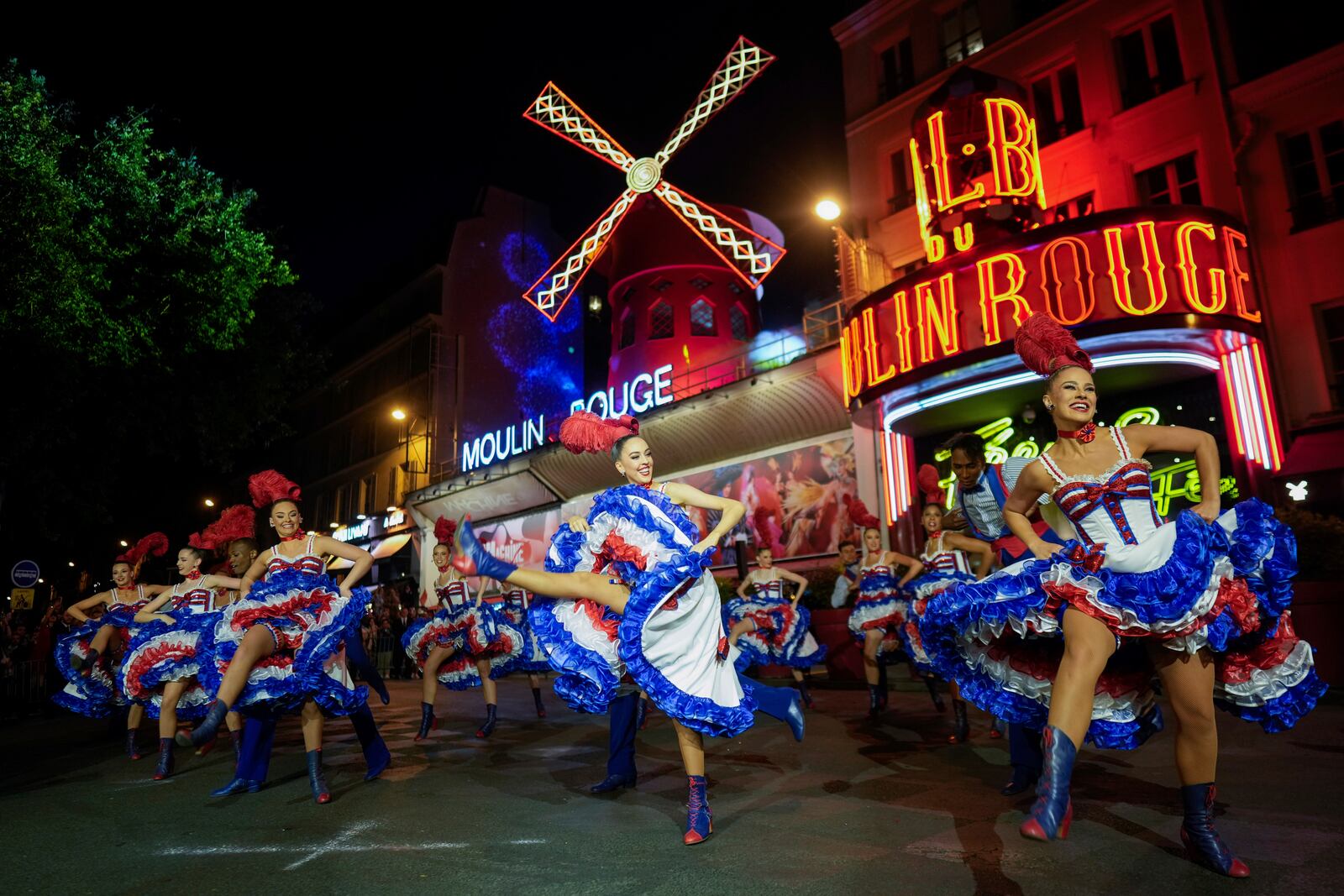 FILE - Dancers perform in front of the Moulin Rouge cabaret during the inauguration of the theatre's windmill in Paris, Friday, July 5, 2024. (AP Photo/Thibault Camus, File)
