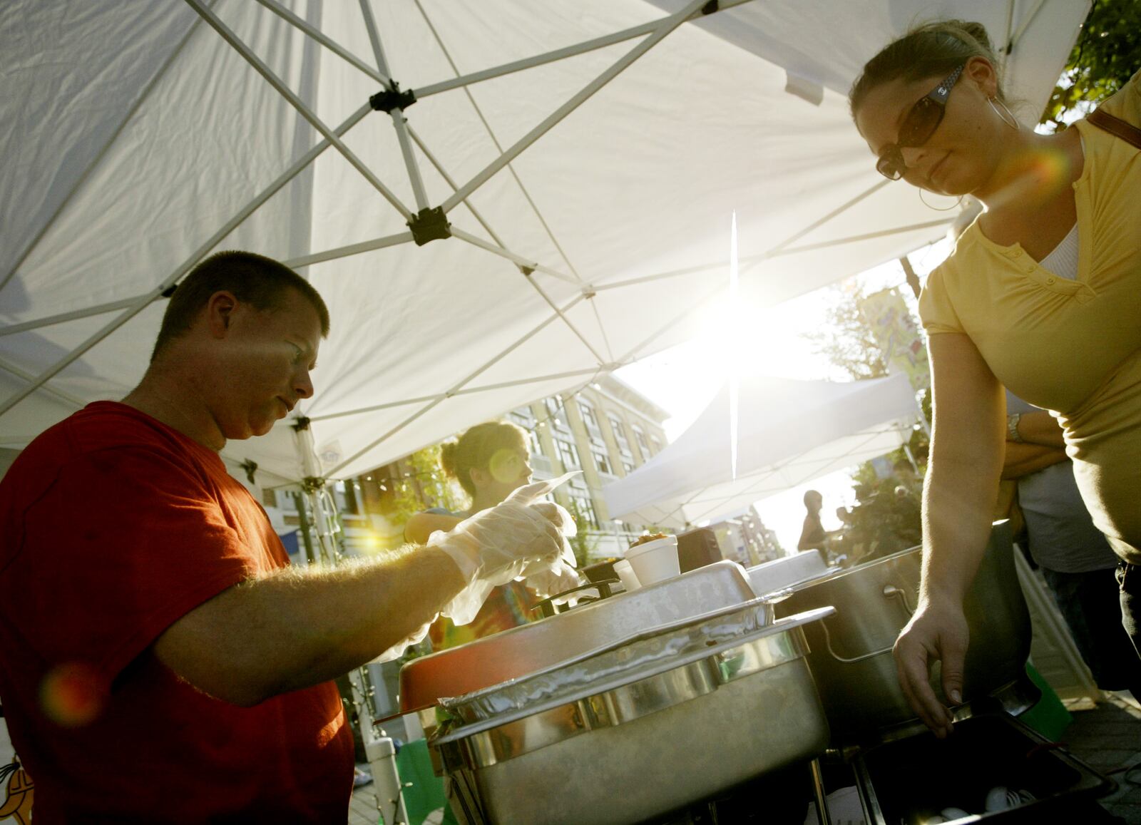 BD's Mongolian Grill employees Ross Wiechinck and Esther Underwood handout rice and chicken stir-fry during the Taste of the Greene on Thursday August 14 at The Greene. Diners paid $10, proceeds benefit Culture Works, to sample dishes from restaurants featured a The Greene.  Staff Photo by Teesha McClam