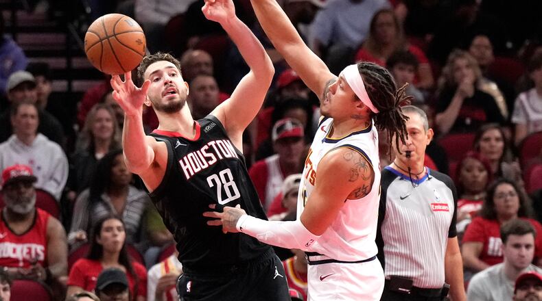 Houston Rockets center Alperen Sengun (28) passes the ball against Denver Nuggets forward Aaron Gordon during the first half of an NBA Cup basketball game, Friday, Nov. 21, 2025, in Houston. (AP Photo/Karen Warren)