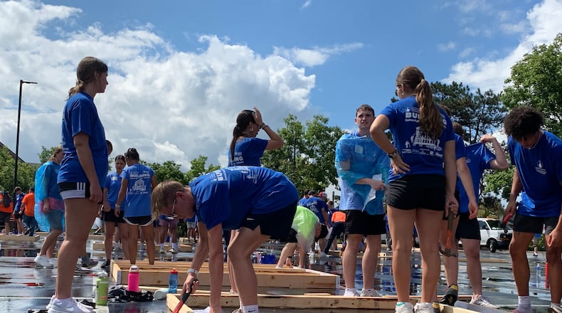 More than 400 University of Dayton students braved pouring rain Sunday to build wood frame walls for Dayton Habitat for Humanity. LONDON BISHOP/STAFF