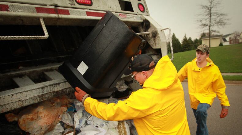 Waste management employees remove residential trash. FILE