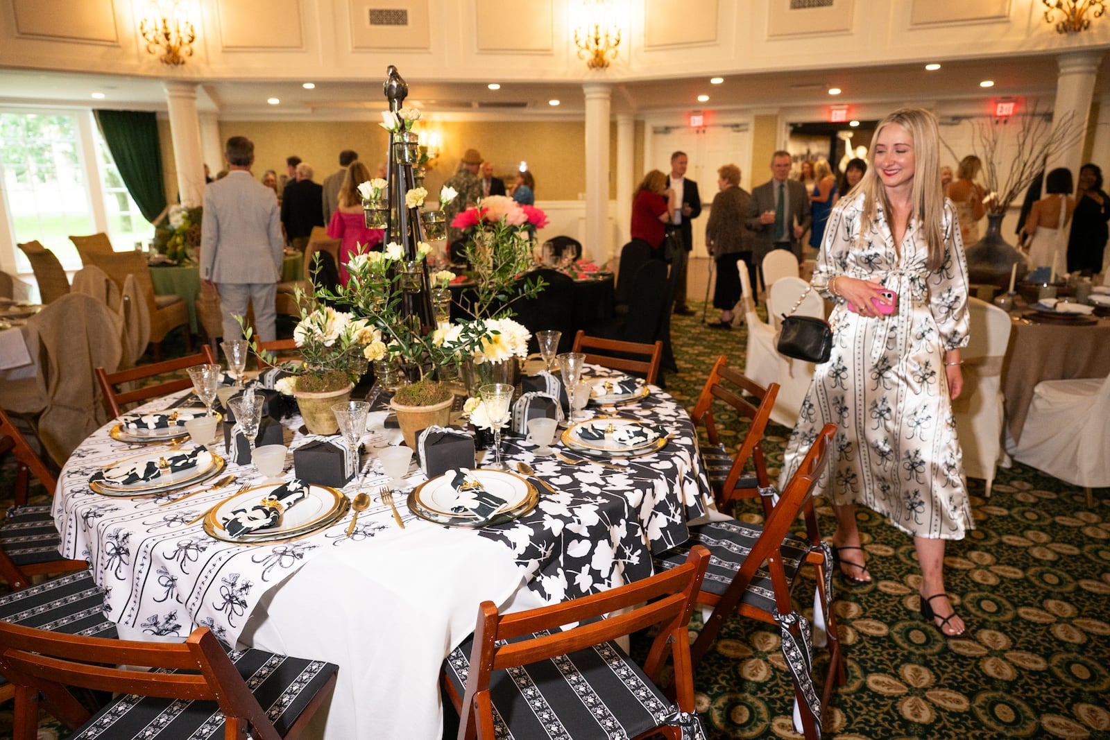 Olivia Richardson with her tablescape at Dayton Dines by Design. “I designed all the textiles. I’m working with different patterns — the stripe, my geranium print.” She also collaborated with a local seamstress to create a satin dress that coordinates with her geranium motif. CONTRIBUTED PHOTO