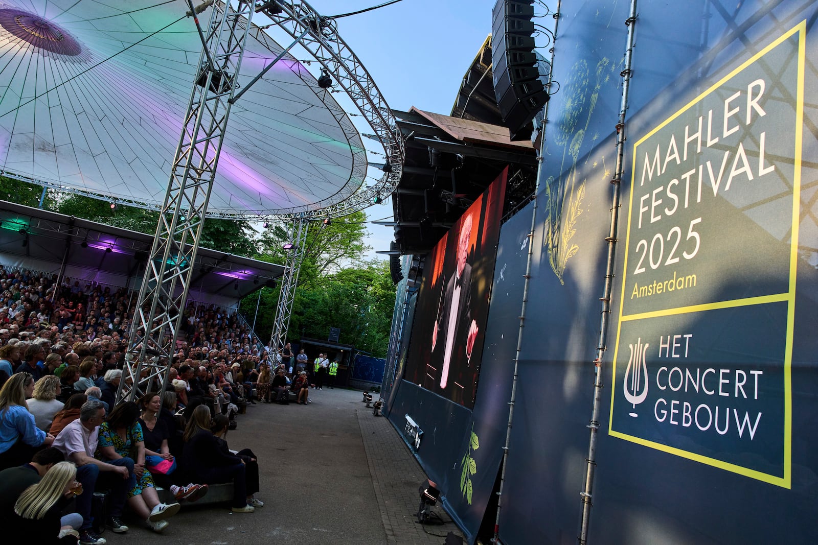 People in Vondelpark watch a video transmission of Ivan Fischer conducting the Budapest Festival Orchestra and the Netherlands Radio Choir performing Mahler's Symphony nr. 2 in the Concertgebouw in Amsterdam, Netherlands, Saturday, May 10, 2025. (AP Photo/Peter Dejong)