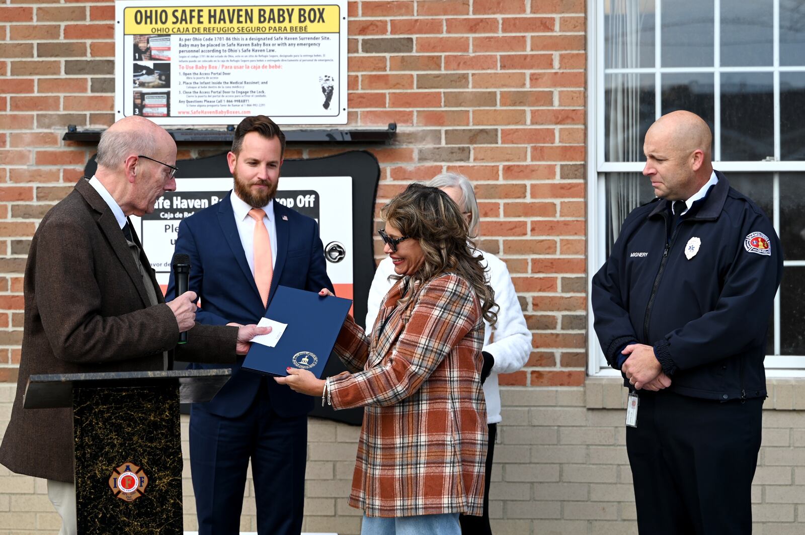Monica Kelsey, of Safe Haven Baby Boxes, the organization named for Ohio's Safe Haven lawn, receives a proclamation on Tuesday afternoon, Nov. 11, 2025, from Hamilton Mayor Pat Moeller on the organization's 20th baby box in Ohio. Hamilton dedicated Butler County's first Safe Haven Baby Box at the Fire Station 22 on Pershing Avenue. The box is designed to allow mothers to anonymously place a newborn baby 30 days or younger in the incubator. Fire personnel are notified through a silent alarm. Mothers can still surrender a baby at any hospital, fire department or police station under Ohio's Safe Haven law. MICHAEL D. PITMAN/STAFF