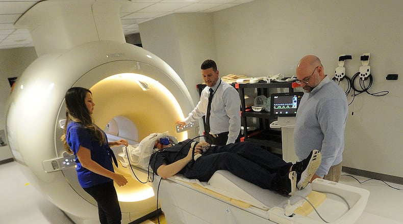 Researchers from left, Stephanie Warner, Biomedical Engineer Naval Medical Reasrarch Unit-Dayton, Joseph Williamitis, Reseach Assistant, David Burch, Resarcher, AFRL/RHBF and Matthew Sherwood, Director, Center of Neuroimaging and Neuro-Evaluation of Cognitive Technologies demonstrates the Wright State MRI machine, Friday Dec. 16, 2022. MARSHALL GORBY\STAFF