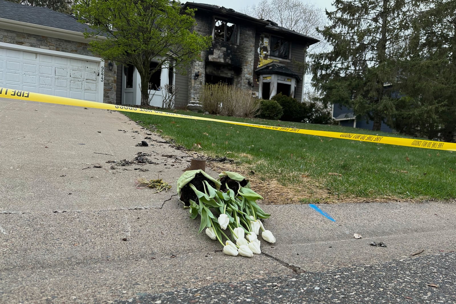 Flowers are left in the driveway at the home of Jill Sobule on Friday, May 2, 2025, in Woodbury, Minn., a day after a fire engulfed the house, killing the 66-year-old singer-songwriter. (AP Photo/Amy Forliti)