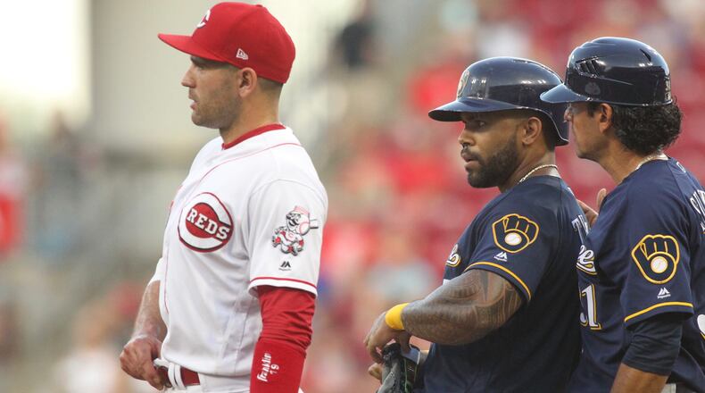 The Brewers Eric Thames, center, stands on first after reaching base against the Reds on Friday, June 29, 2018, at Great American Ball Park in Cincinnati. David Jablonski/Staff