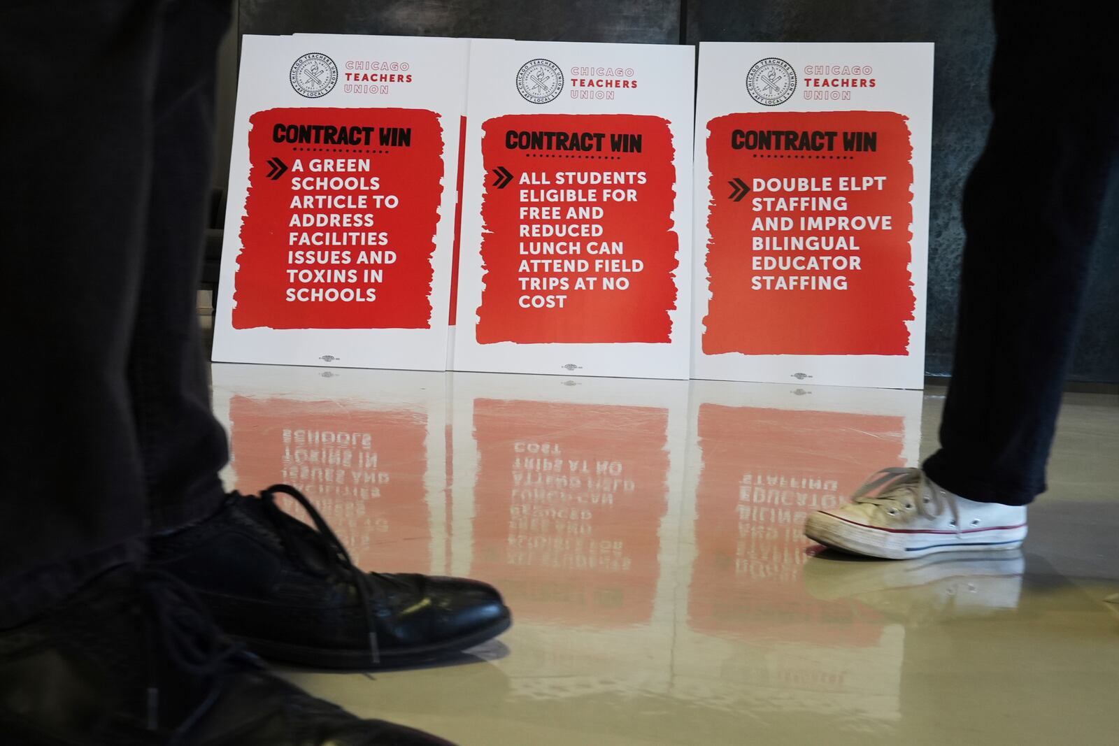 Signs are displayed during news conference for Teachers Union to Announce Historic Contract Ratification Vote Results at CTU headquarters in Chicago, Monday, April 14, 2025. (AP Photo/Nam Y. Huh)