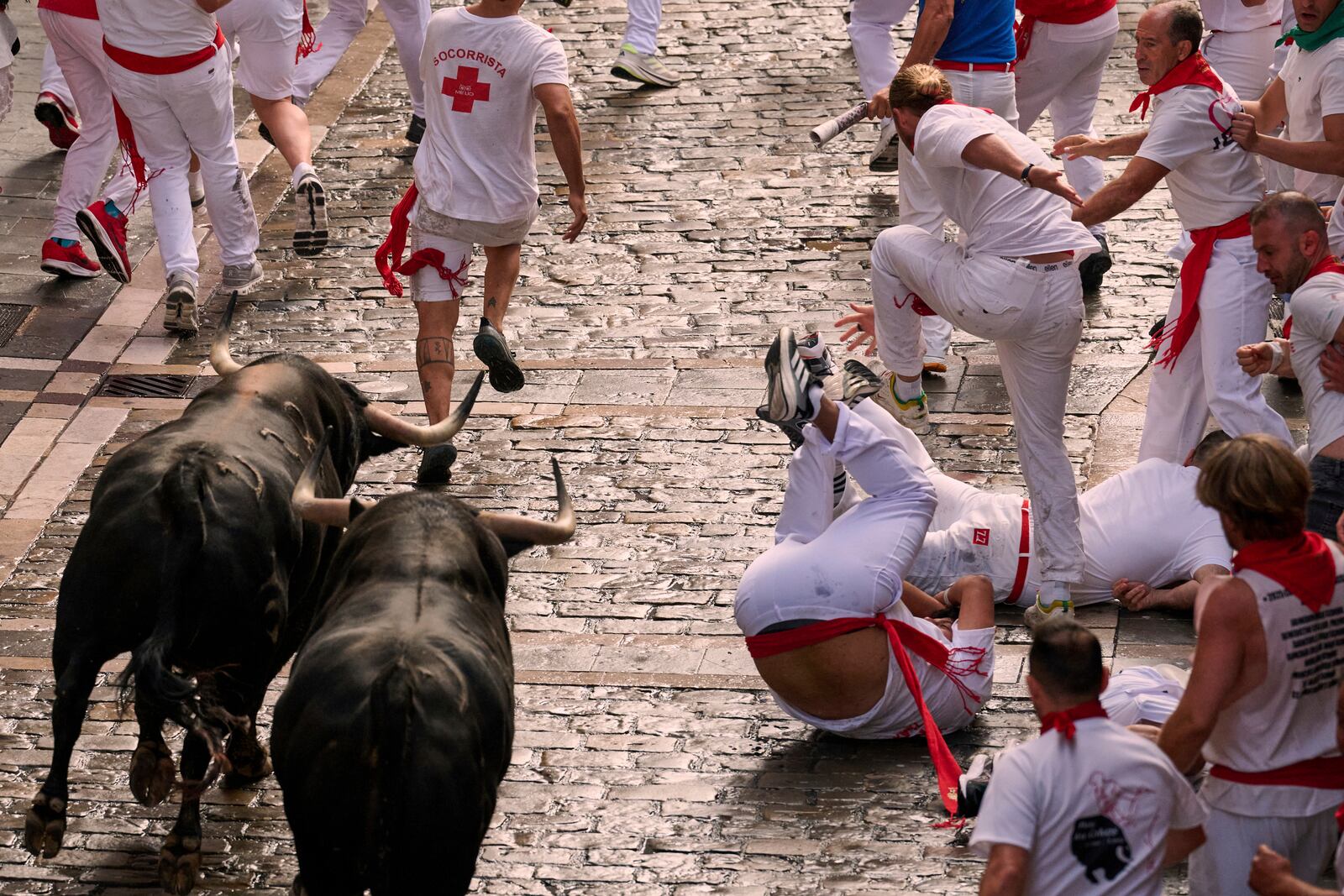 Revelers run with bulls from Fuente Ymbro ranch during the first day of the running of the bulls at the San Fermín fiestas in Pamplona, Spain, Monday, July 7, 2025. (AP Photo/Miguel Oses)