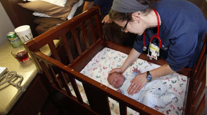 Karis (CQ) Russell (right) a clinical nurse at Miami Valley Hospital’s Family Beginnings Birthing Center, demonstrates safe sleep techniques for Laura Craig of Jeffersonville who delivered her son Malachi Monday night. LISA POWELL / STAFF
