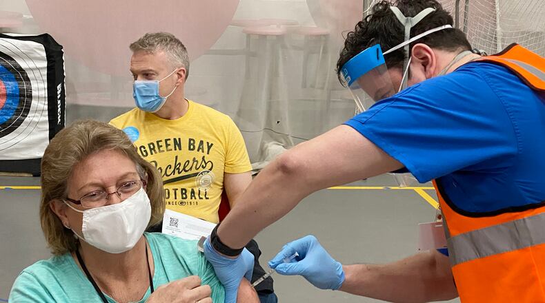 Roberta Wells, a bus driver for Troy City Schools, gets her first dose of COVID-19 vaccine Friday, Feb. 26, as guidance counselor Paul Delwiche waits his turn. Troy schools partnered with Premier Health to offer the vaccinations. School employees in Troy will get their second dose March 19. CONTRIBUTED PHOTO