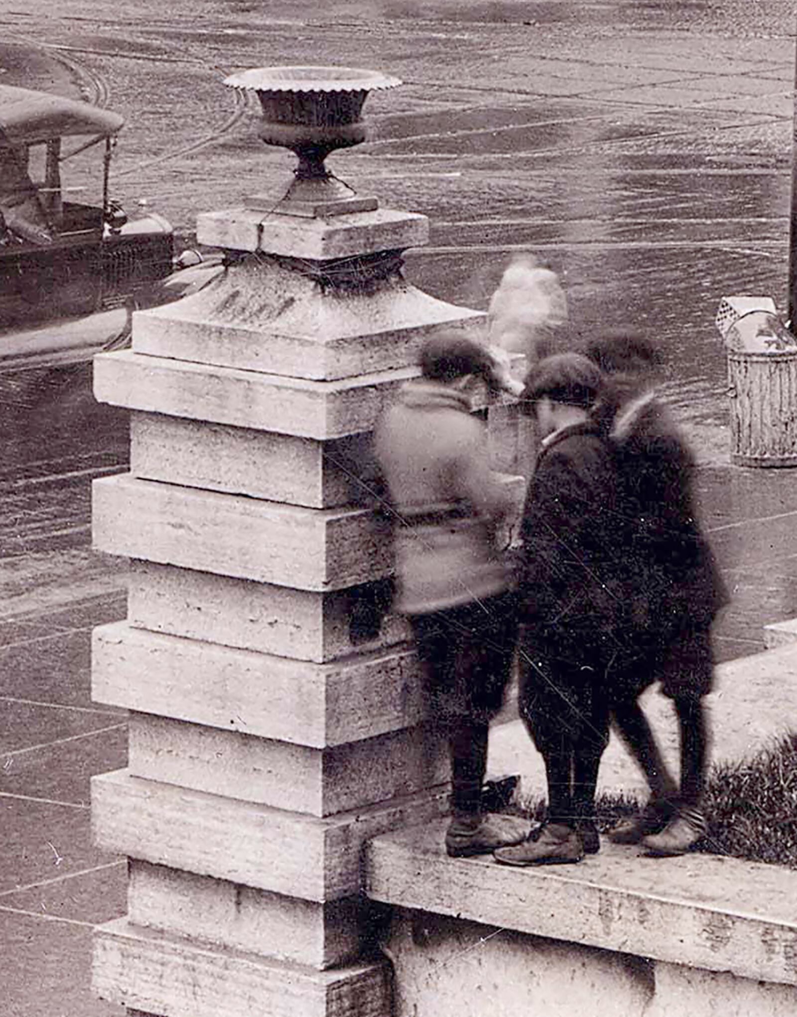 Three boys huddled together behind a pillar in front of the Old Courthouse, all three outfitted in knickers and caps. DAYTON METRO LIBRARY / LUTZENBERGER PICTURE COLLECTION