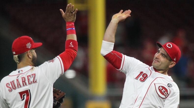 Reds first baseman Joey Votto, right, and third baseman Eugenio Suarez celebrate after the final out of a victory against the Braves on Tuesday, April 23, 2019, at Great American Ball Park in Cincinnati. David Jablonski/Staff