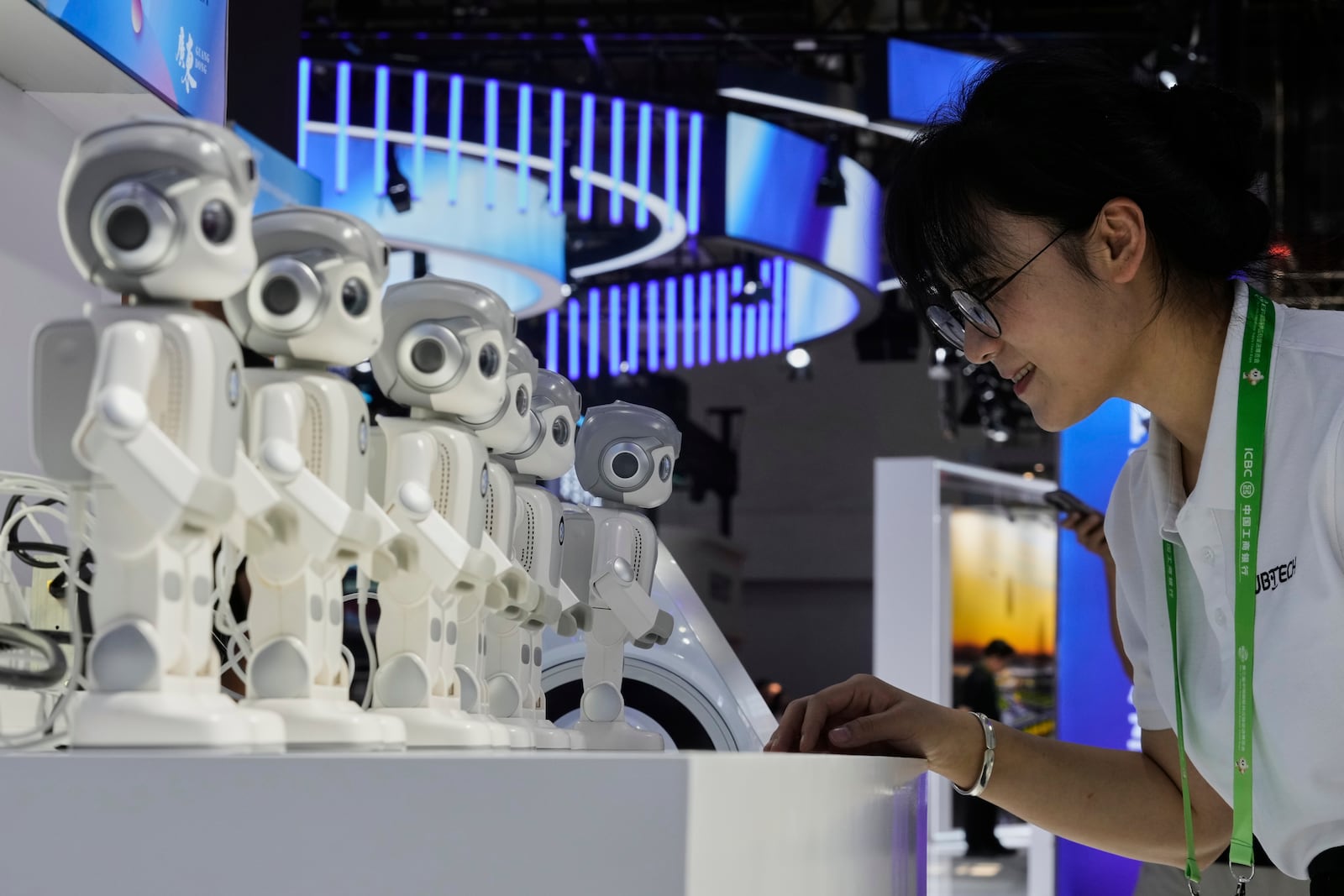 An exhibitor gives a command to a Ubtech humanoid robot at a booth during the 3rd China International Supply Chain Expo at the China International Exhibition Center, in Beijing, China, Friday, July 18, 2025. (AP Photo/Mahesh Kumar A.)