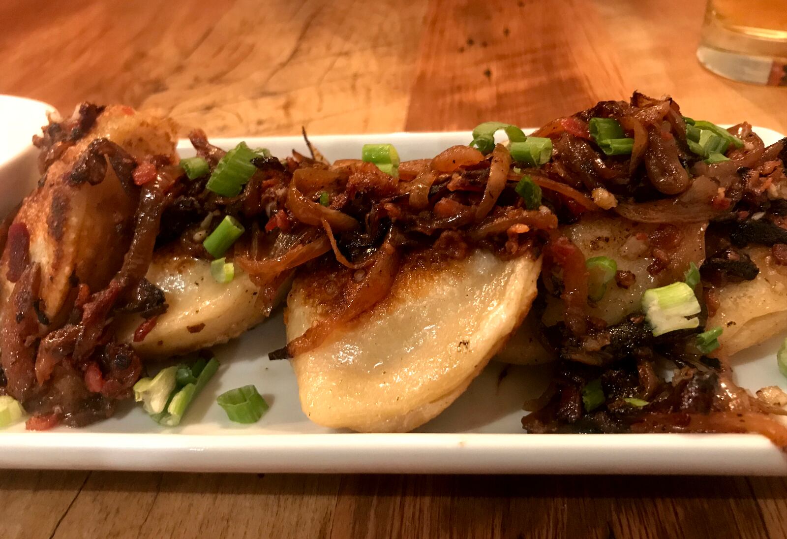 The food at Lock 27 in downtown Dayton. Pictured: 
Potato and cheddar pierogies topped with bacon, sautéed onions and garlic.  They are served with  sour cream. Photo by Amelia Robinson