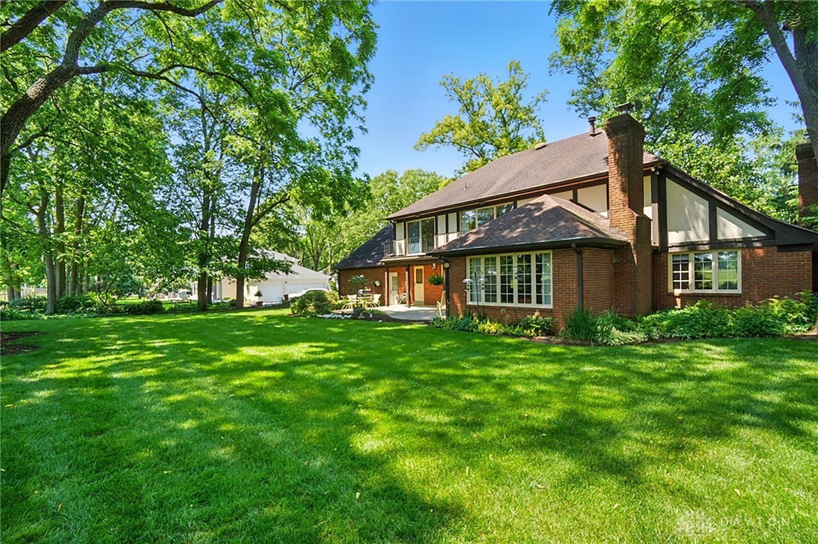 the back of the home features a partially covered patio and upper level balcony with access from the primary suite and another bedroom.