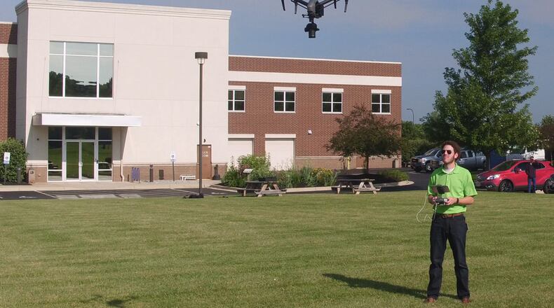 Ethan Schreuder, a survey technician and UAS pilot for Woolpert, flies an unmanned aerial systems craft outside Woolpert headquarters in the summer of 2018. FILE