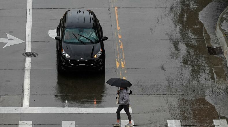 FILE - A pedestrian crosses the street in front of a car May 12, 2024, in Denver. (AP Photo/David Zalubowski, File)