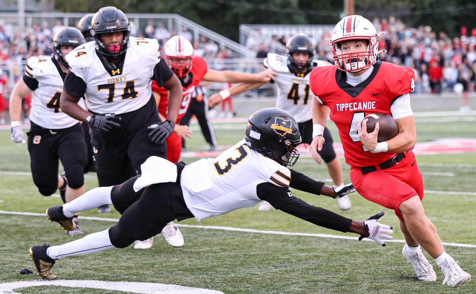 Tippecanoe junior quarterback Larkin Thomas runs while trying to avoid Sidney's Demarcuse Fleming during a Miami Valley League game on Thursday, Sept. 24 at City Park in Tipp City. BRYANT BILLING / STAFF