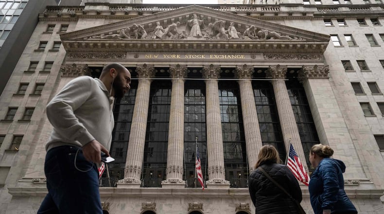 People walk past the New York Stock Exchange, Friday, March 27, 2026, in New York. (AP Photo/Yuki Iwamura)