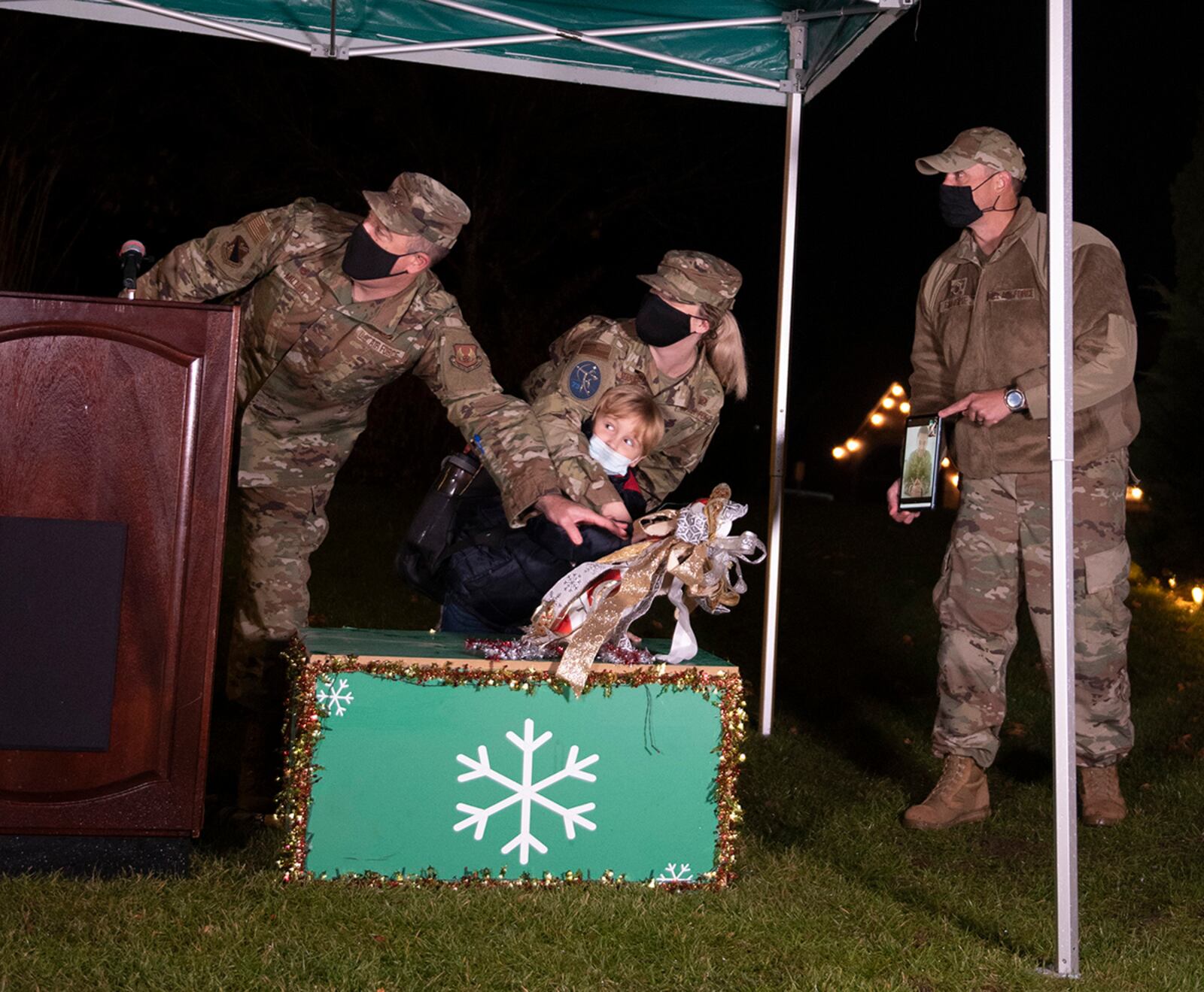 Col. Patrick Miller, 88th Air Base Wing and installation commander, is joined by the family of a deployed Airman to flip the switch and light the Wright-Patterson Air Force Base Christmas tree Dec. 1. U.S. AIR FORCE PHOTO/JAIMA FOGG