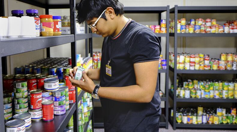 In this Feb. 5, 2016, photo, Vedant Kale, a first-year finance student from Aurangabad, India, shelves donated food in a new pantry at the University of Toledo. Photo by Jetta Fraser/The Blade