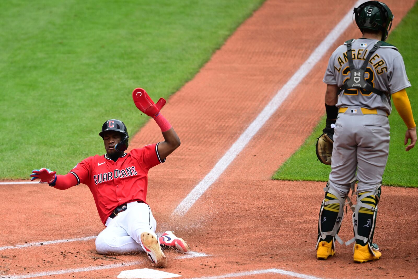 Cleveland Guardians' Angel Martínez slides safely into home plate to score a run on an RBI-single by David Fryduring the first inning of a baseball game against the Athletics, Sunday, July 20, 2025, in Cleveland. (AP Photo/David Dermer)
