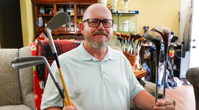 Kevin Dick poses with some of the vintage MacGregor golf clubs his father, Robert, made and collected over the course of his career working for the company. GREG LYNCH/STAFF