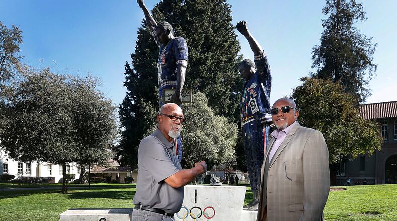 FILE - In this Oct. 17, 2018, file photo, John Carlos, left, and Tommie Smith pose for a photo in front of statue that honors their iconic, black-gloved protest at the 1968 Olympic Games, on the campus of San Jose State University in San Jose, Calif. Smith, Carlos and Gwen Berry are among the more than 150 educators, activists and athletes who signed a letter Thursday, July 22, 2021, urging the IOC not to punish participants who demonstrate at the Tokyo Games. ( (AP Photo/Tony Avelar, File)