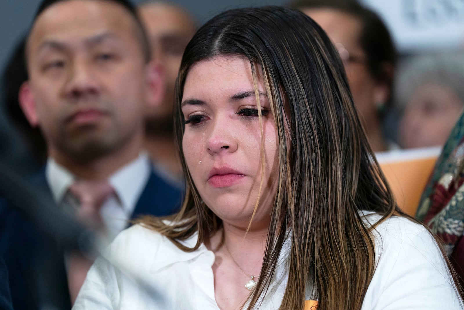 Jennifer Vasquez Sura cries as Sen. Chris Van Hollen, D-Md., speaks during a news conference upon his arrival from meeting with her husband Kilmar Abrego Garcia in El Salvador, at Washington Dulles International Airport, in Chantilly, Va., Friday, April 18, 2025. (AP Photo/Jose Luis Magana)