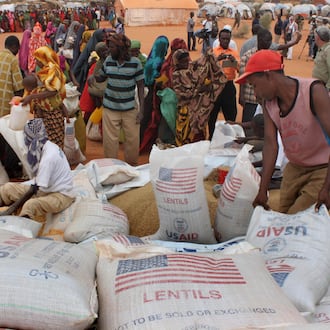 FILE - Workers distribute food aid from the World Food Program at a refugee camp in Dolo, Somalia on July 18. 2012. (AP Photo/Jason Straziuso, file)