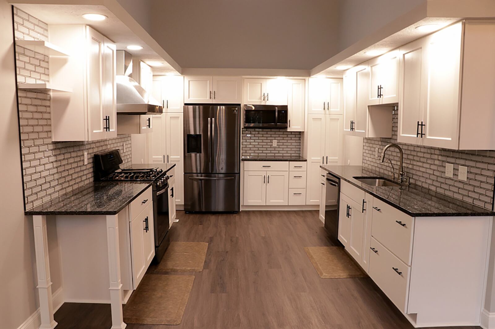Tucked off the dining area is the redesigned U-shaped kitchen. White cabinetry fills three walls and wraps around black-steel appliances. Granite countertops complement the flooring and highlight the glass-brick backsplash. CONTRIBUTED PHOTO BY KATHY TYLER