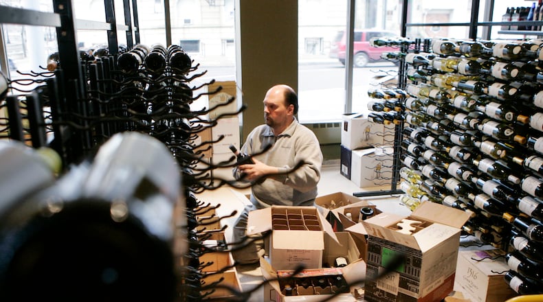 Brian Lennean, former proprietor of The Wine Gallery, places bottles of wine on racks in this 2010 photos. FILE.