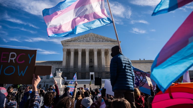 Protesters wave transgender pride flags outside the Supreme Court as it hears arguments over state laws barring transgender girls and women from playing on school athletic teams, Tuesday, Jan. 13, 2026, in Washington. (AP Photo/Julia Demaree Nikhinson)