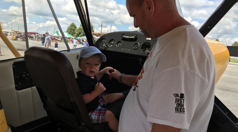 Wyatt Sexton, 18 months, of Xenia experiences what the cockpit of a 1946 Aeronca 7AC Champion aircraft is like with help from owner Duane Jones of New Carlisle at the fourth Barnstorming Carnival at Springfield-Beckley Municipal Airport on Saturday. BRETT TURNER