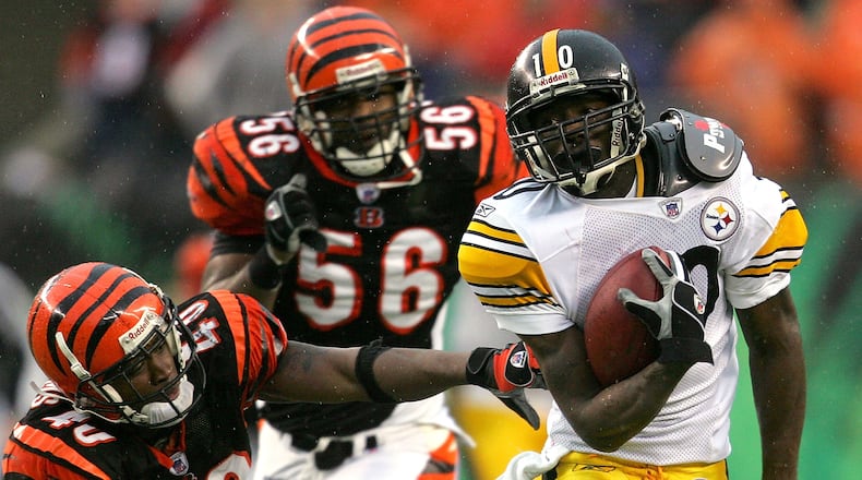 CINCINNATI - DECEMBER 31: Santonio Holmes #10 of the Pittsburgh Steelers eludes Madieu Williams #40 of the Cincinnati Bengals en route to a touchdown in overtime on December 31, 2006 at Paul Brown Stadium in Cincinnati, Ohio. The Steelers defeated the Bengals 23-17. (Photo by Matthew Stockman/Getty Images)