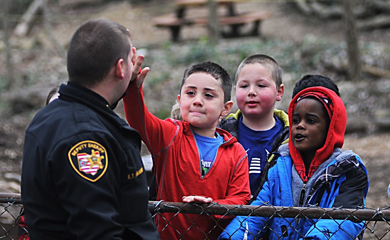 Montgomery county deputy Scott Hammond high-fives students from the Gloria Dei Montessori School Monday, while assisting with an accident in front of the school. MARSHALL GORBY/STAFF