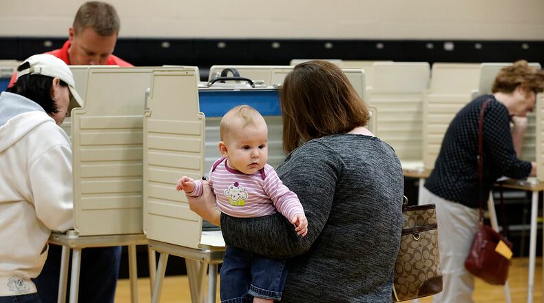 Five-month-old Margaret Russell looks around gymnasium at Tecumseh High School as her mother holds her while casting her vote at the election poll there. Bill Lackey/Staff
