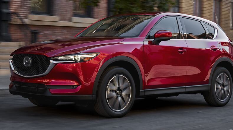 The entry 2017 Mazda CX-5 Sport trim features 17-inch alloy wheels, black cloth-upholstered seats, cruise control, air conditioning, power windows, power mirrors, pushbutton starter, LED headlights, variable intermittent windshield wipers, carpeted floor mats, a 40:20:40 split-folding rear seat, Smart City Brake Support and power door locks. Mazda photo