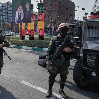 Policemen stand guard next to the banners showing portraits of the late Iranian Supreme Leader Ayatollah Ali Khamenei at the Enqelab-e-Eslami, or Islamic Revolution, square in downtown Tehran, Iran, Saturday, March 14, 2026. (AP Photo/Vahid Salemi)