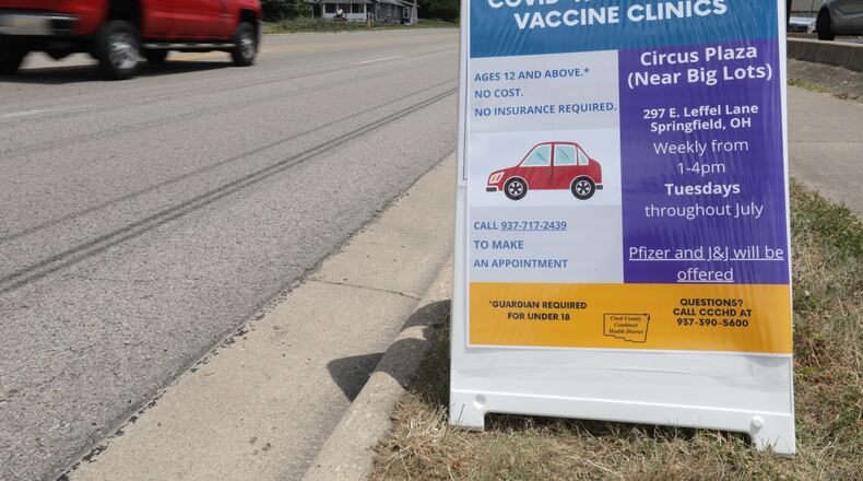 Cars drive past a sign for a free drive-thru COVID-19 vaccine clinic in the Circus Plaza on East Leffel Lane Tuesday. BILL LACKEY/STAFF