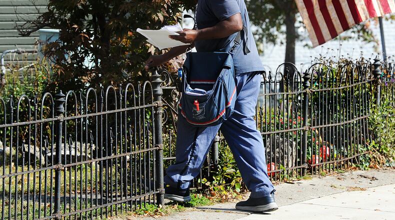 A postal worker delivers his route on Oak Street Wednesday, Oct. 18, 2023 in Dayton. MARSHALL GORBY\STAFF