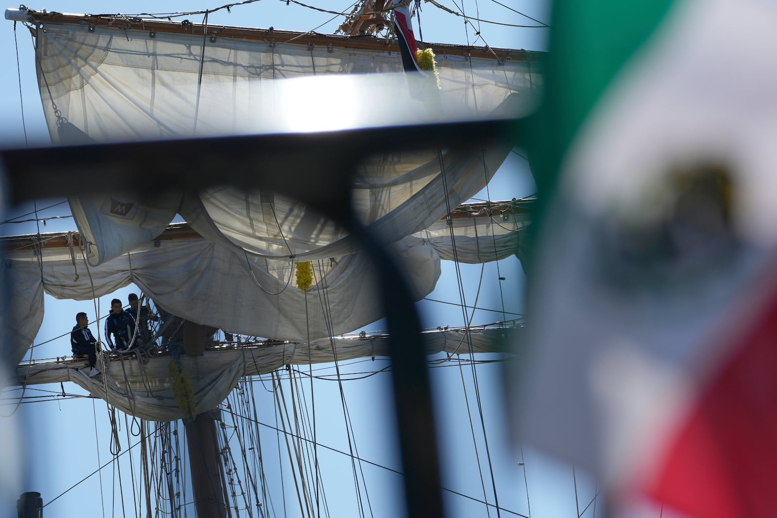 A Mexican flag is displayed on a fence near the Cuauhtemoc, a masted Mexican Navy training ship, after it collided with the Brooklyn Bridge in New York, Monday, May 19, 2025. (AP Photo/Seth Wenig)