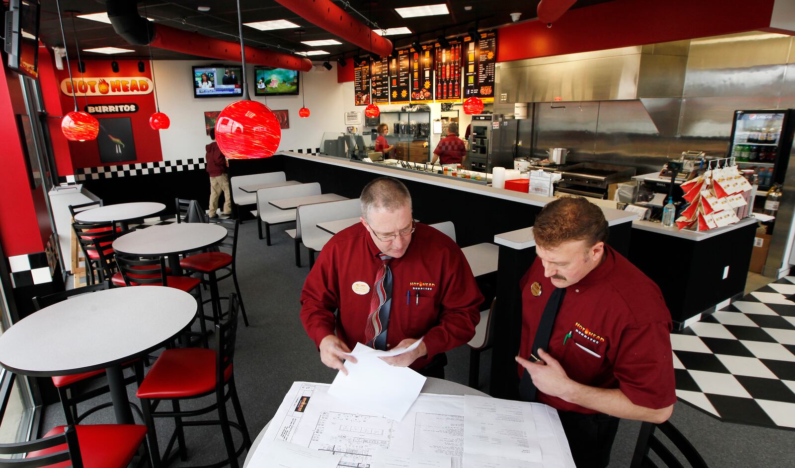 Co-founder of the Hot Head Burritos chain Raymond Wiley, left, and franchise owner Kevin Foley discuss future plans at the Fairborn location on Dayton-Yellow Springs Road in this 2012 photo. CHRIS STEWART/STAFF
