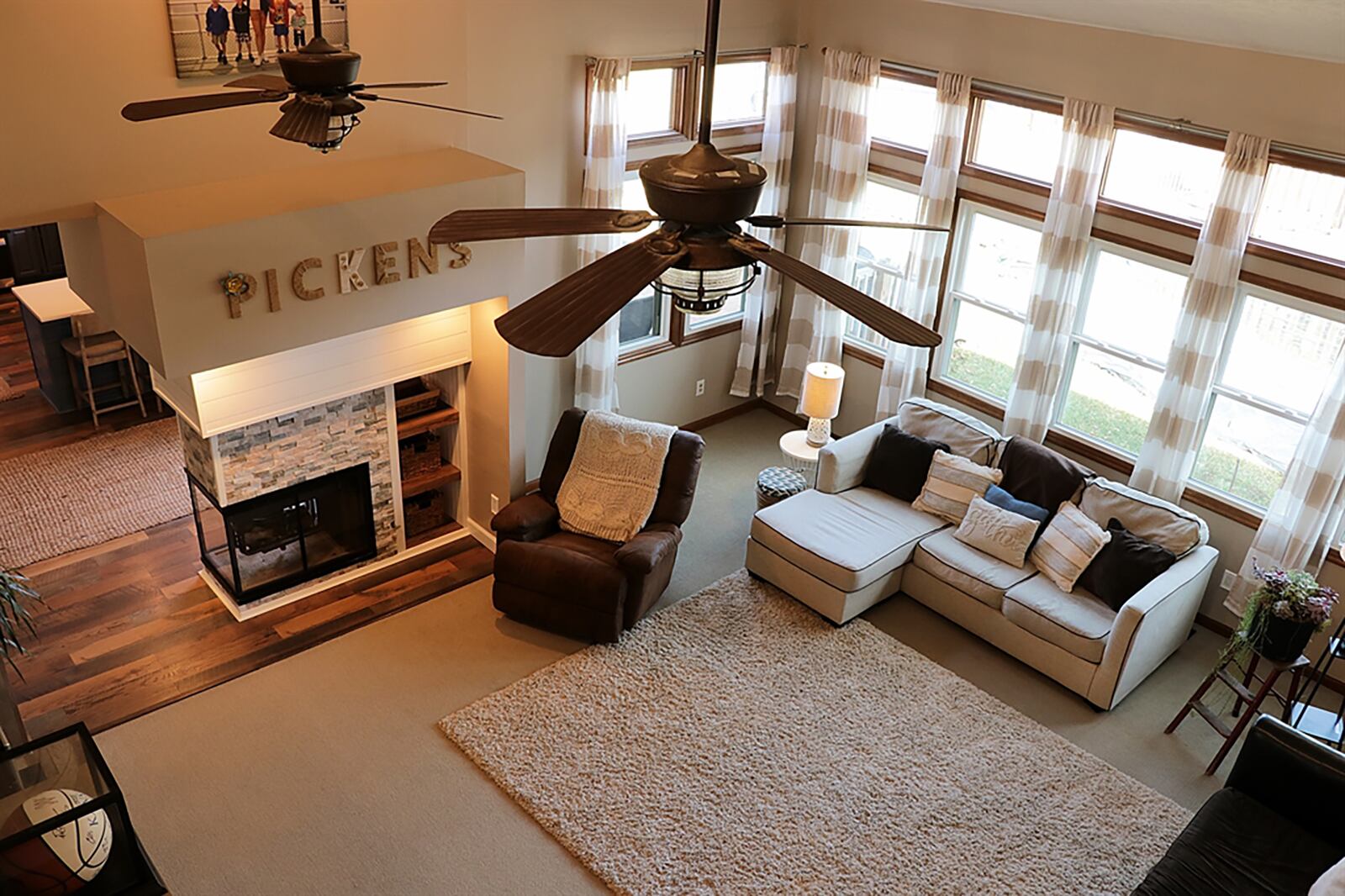 At the end of the foyer hallway and under the catwalk is the great room that has a wall of tall windows and a vaulted ceiling with 2 paddle ceiling fans. A triple-sided, gas fireplace has been redesigned with stack stone and shipboard surround, a built-in display shelf and accent lighting. CONTRIBUTED PHOTO BY KATHY TYLER