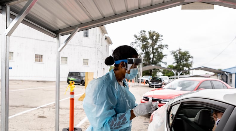 A worker collects a test specimen at Premier Health and CompuNet's OnMain testing site in September. The testing site is closing down as demand plummets. CONTRIBUTED