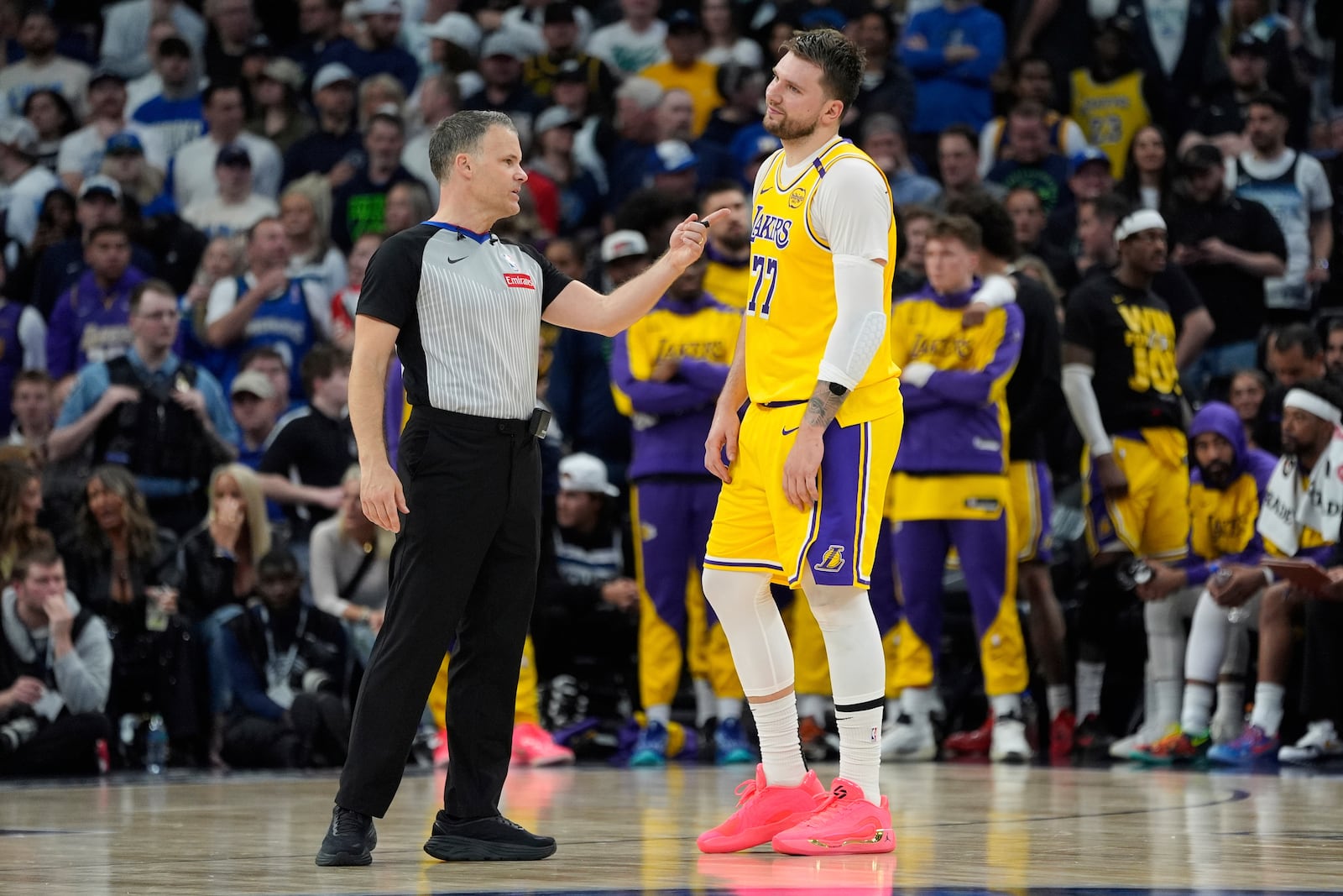 Los Angeles Lakers guard Luka Doncic (77) stands next to referee Mark Lindsay during the second half of Game 3 of an NBA basketball first-round playoff series against the Minnesota Timberwolves, Friday, April 25, 2025, in Minneapolis. (AP Photo/Abbie Parr)