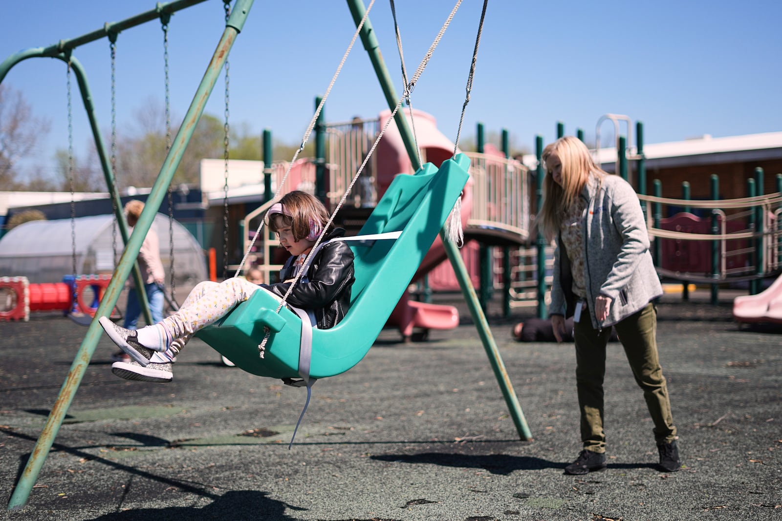 Aria takes a ride on a swing while accompanied by teacher Tricia Cadle at Archbishop Damiano School in Westville, N.J., Wednesday, April 9, 2025. (AP Photo/Matt Rourke)
