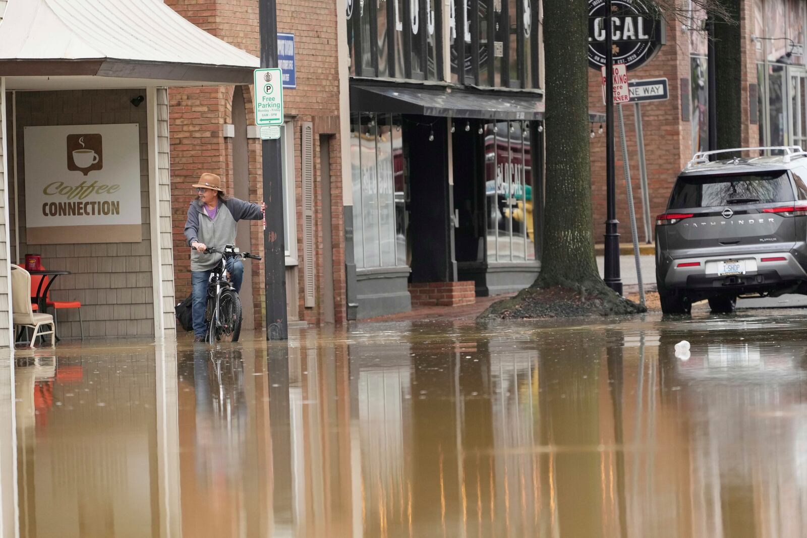 A person rides a bike in a flooded street in Hopkinsville, Ky., Friday, April 4, 2025. (AP Photo/George Walker IV)