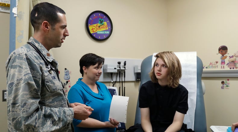 In this Sept. 7, 2016, photo, Dr. David Klein, an Air Force Major and chief of adolescent medicine at Fort Belvoir Community Hospital, left, speaks with Amanda Brewer and her daughter Jenn Brewer, 13, during the teenager's regular monthly doctors appointment for monitoring of her treatment at the hospital in Fort Belvoir, Va. Brewer is transitioning from male to female. Starting Oct. 3, the military’s health insurance will cover transgender-related services that include hormone therapy and supportive counseling.(AP Photo/Jacquelyn Martin)